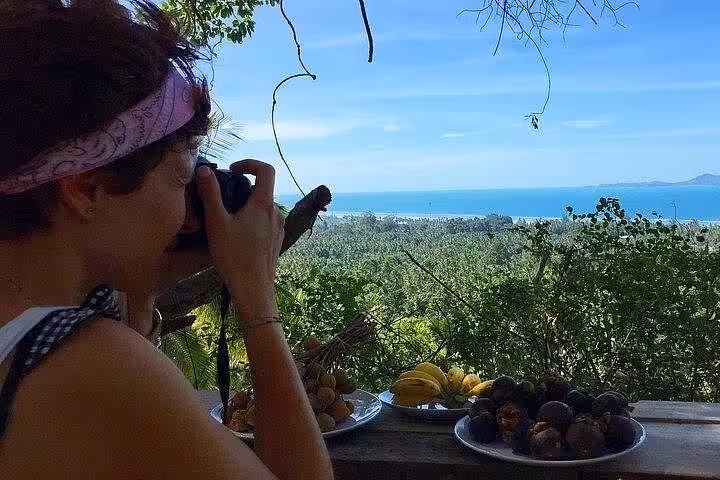 Tourist enjoying traditional Thai lunch with ocean view during private Koh Phangan island tour with tropical fruit and coastal scenery
