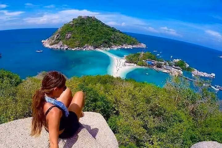 Tourist enjoying panoramic view from Koh Nang Yuan viewpoint overlooking famous sand bridge connecting three islands during speedboat tour from Koh Phangan