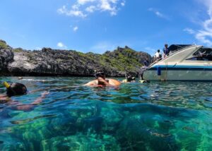 Snorkeling tour with speedboat at limestone cliffs in crystal clear turquoise waters, Thailand