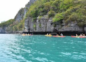 Sea kayaking tour group exploring limestone cliffs and emerald waters in Thailand marine park