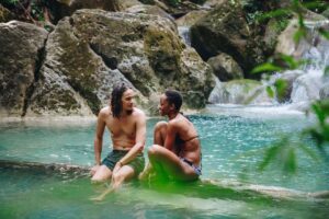 Couple relaxing in natural waterfall pool surrounded by tropical rocks in Koh Samui jungle