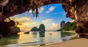 Krabi's Phra Nang Cave Beach sunset with limestone cliffs and golden sky viewed through cave opening