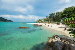 Tourists traveling to Koh Lipe Sunrise Beach by traditional long-tail boat during golden hour, Thailand